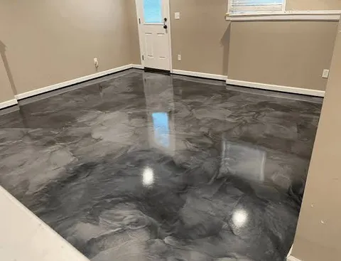 Finished basement room with tan walls and a dark charcoal and silver metallic epoxy floor