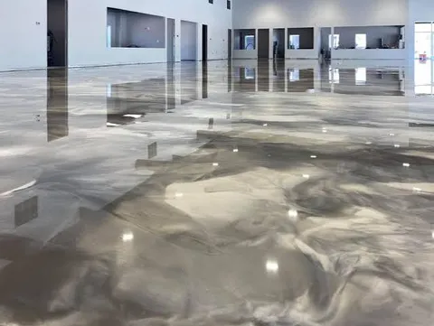 Large open commercial showroom with a pearl and gray marbled metallic epoxy floor reflecting the lights